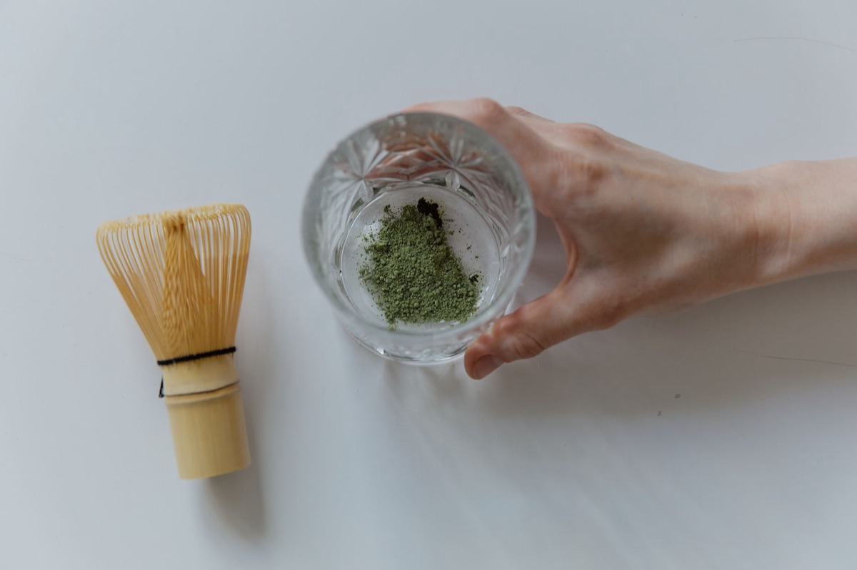 Pó de matcha verde vibrante ao lado de um batedor de bambu tradicional (chasen).