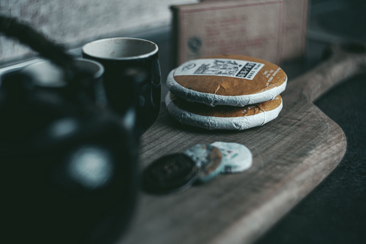 Dark aged Pu-erh tea cake stacked on a wooden table