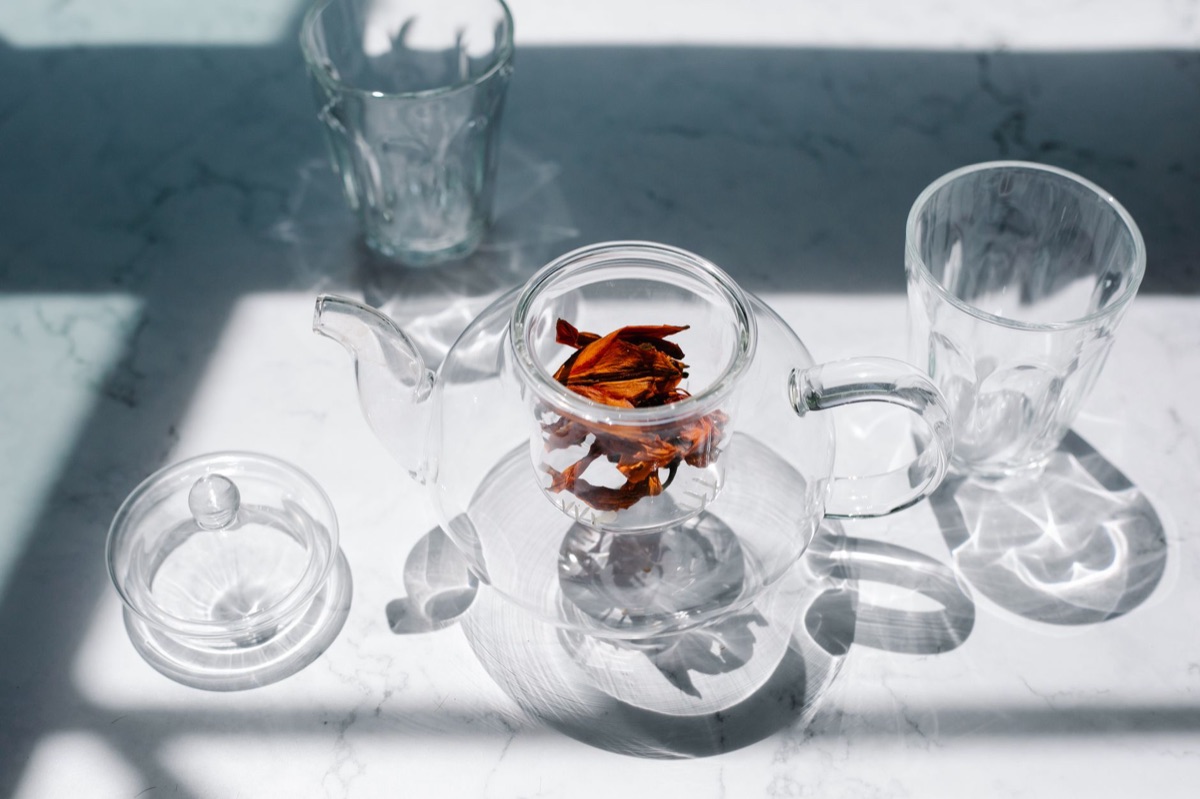 A glass teapot showing dark tea infusion and tea leaves swirling