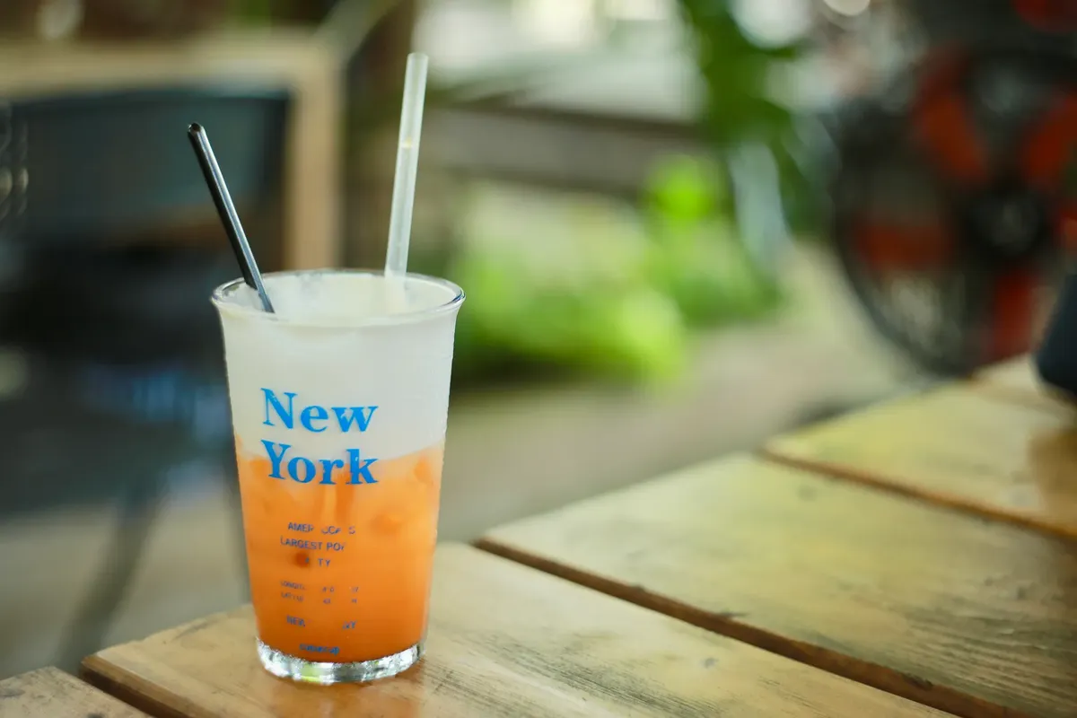 Iced drink in transparent cup with New York text on wooden table