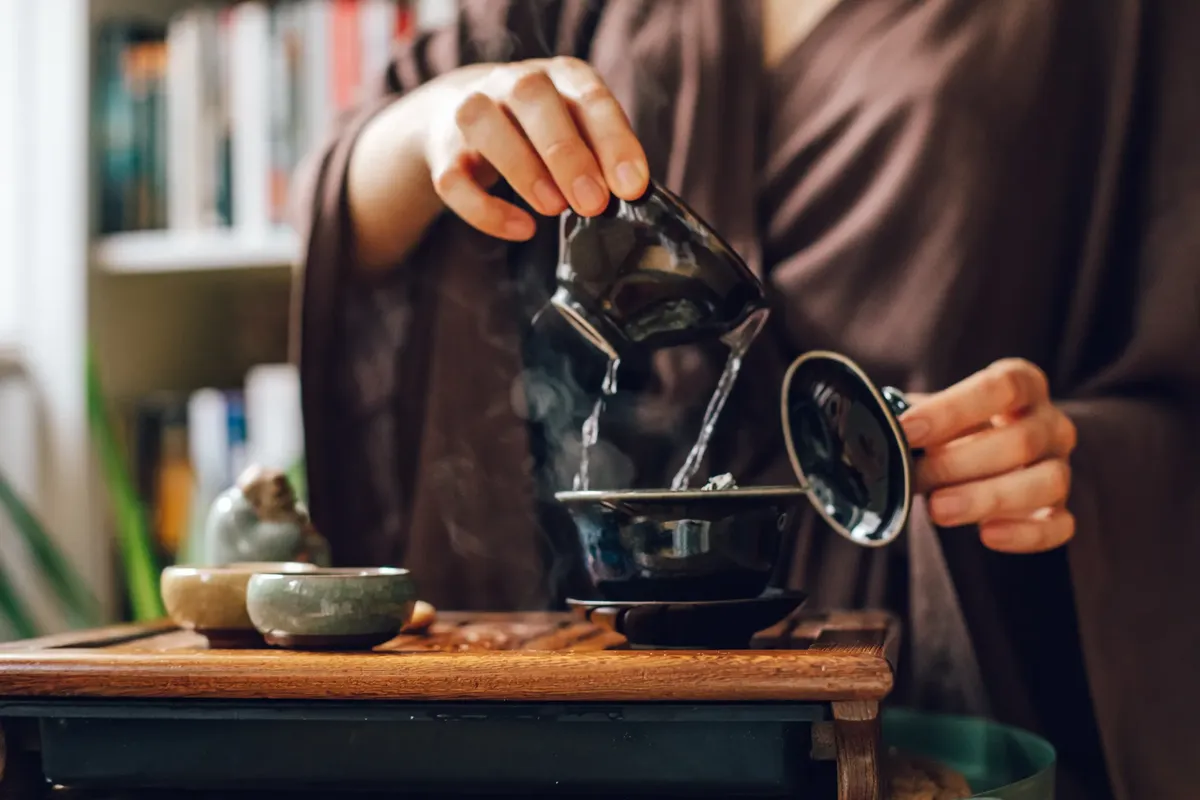 A serene close-up of a traditional tea ceremony, focusing on a teapot and pouring tea.